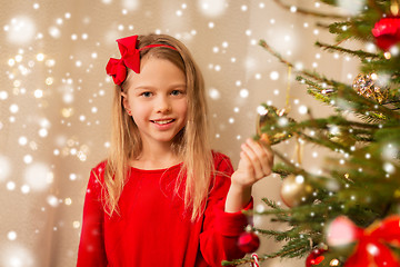 Image showing happy girl in red decorating christmas tree
