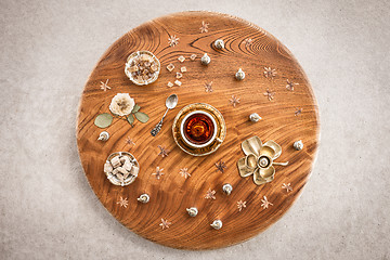 Image showing Round wooden table with tea and flowers