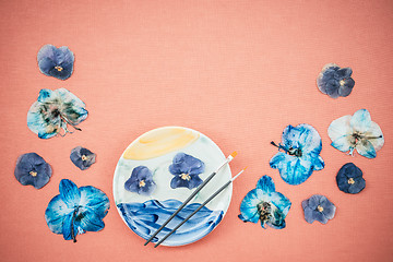 Image showing Blue pansies and painted ceramic plate