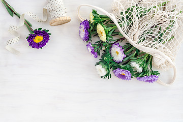 Image showing Asters in a mesh bag on white wooden background