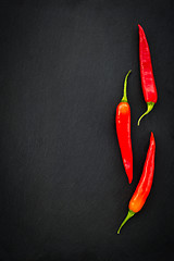 Image showing Three red chili peppers on dark background