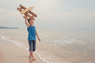 Image showing Little boy playing with cardboard toy airplane on the beach