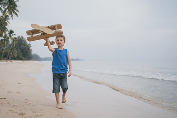Image showing Little boy playing with cardboard toy airplane on the beach
