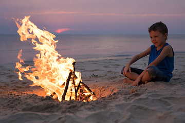 Image showing One happy little boy playing on the beach at the sunset time.