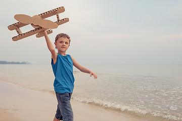 Image showing Little boy playing with cardboard toy airplane on the beach