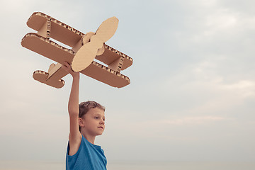 Image showing Little boy playing with cardboard toy airplane on the beach