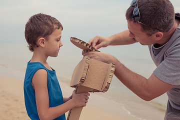 Image showing Father and son playing with cardboard toy airplane