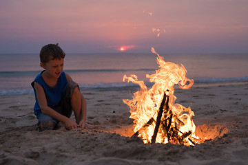 Image showing One happy little boy playing on the beach at the sunset time.