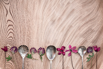 Image showing Wild flowers and silver spoons on wooden surface