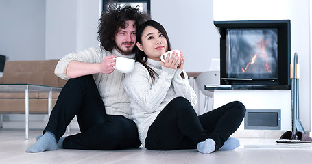 Image showing multiethnic romantic couple  in front of fireplace