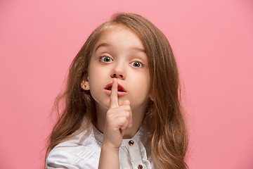 Image showing The young teen girl whispering a secret behind her hand over pink background