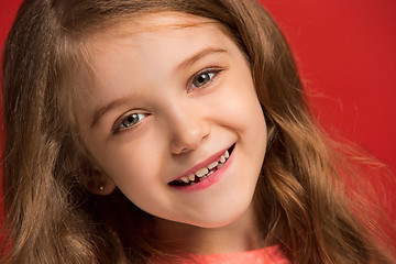 Image showing The happy teen girl standing and smiling against red background.