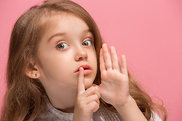 Image showing The young teen girl whispering a secret behind her hand over pink background