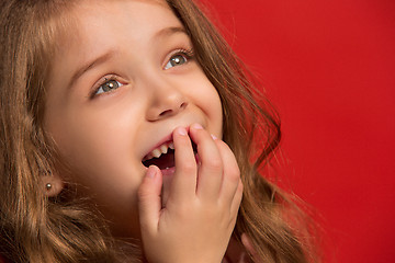 Image showing The happy teen girl standing and smiling against red background.