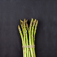 Image showing Bunch of fresh raw garden asparagus on black board background.