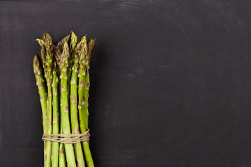 Image showing Bunch of fresh raw garden asparagus on black board background.