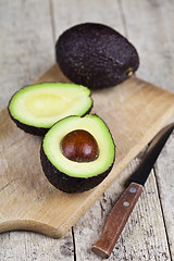 Image showing Avocado and knife on cutting board on old wooden table backgroun