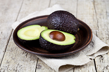 Image showing Fresh organic avocado on ceramic plate and linen napkin on rusti