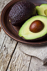 Image showing Fresh organic avocado on ceramic plate and linen napkin on rusti