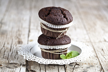 Image showing Two fresh dark chocolate muffins with mint leaves on white plate