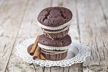 Image showing Fresh dark chocolate muffins with cinnamon sticks on white plate