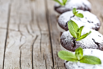 Image showing Fresh chocolate dark muffins with sugar powder and mint leaf on 