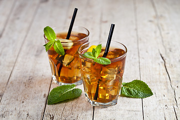 Image showing Cold iced tea with lemon, mint leaves and ice cubes in two glass