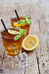 Image showing Cold iced tea with lemon, mint leaves and ice cubes in two glass