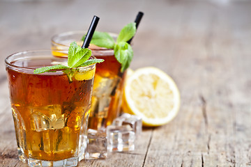 Image showing Cold iced tea with lemon, mint leaves and ice cubes in two glass