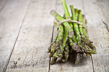 Image showing Bunch of fresh raw garden asparagus on rustic wooden table backg