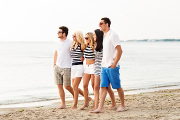 Image showing friends in striped clothes walking along beach