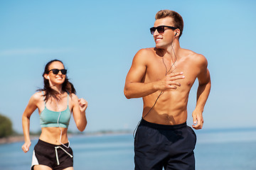 Image showing couple with earphones running along on beach