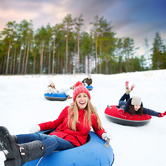 Image showing happy friends sliding down hill on snow tubes