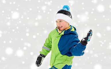 Image showing happy boy playing and throwing snowball in winter