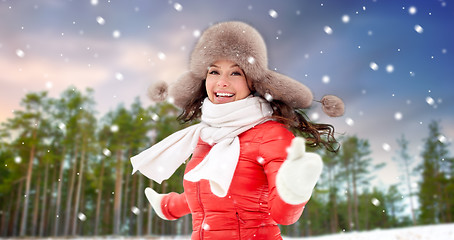 Image showing happy woman in fur hat over winter forest