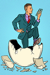 Image showing The businessman was born from an egg. Reads news in the smartphone