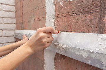 Image showing Hand draws a horizontal line with a pencil on the wall using aluminum rule