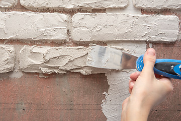 Image showing Plasterer manually works with a spatula and smooths the plaster on the wall