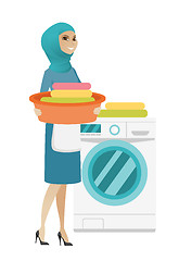 Image showing Muslim housewife using washing machine at laundry.