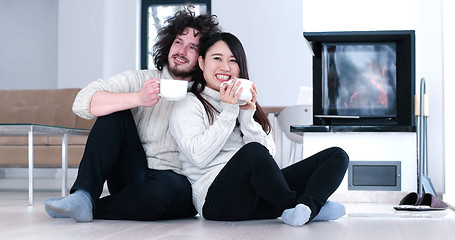 Image showing multiethnic romantic couple  in front of fireplace