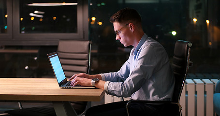 Image showing man working on laptop in dark office