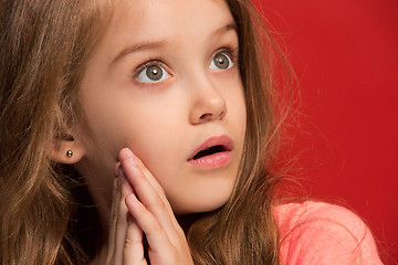 Image showing Beautiful teen girl looking suprised isolated on red