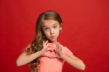 Image showing The happy teen girl standing and smiling against red background.