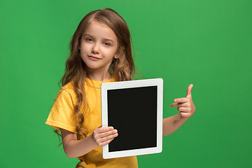 Image showing Little funny girl with tablet on green background