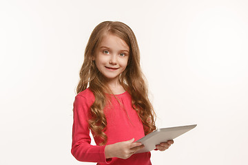 Image showing Little funny girl with tablet on green background