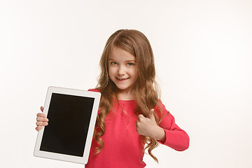 Image showing Little funny girl with tablet on green background