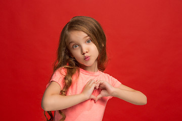 Image showing The happy teen girl standing and smiling against red background.