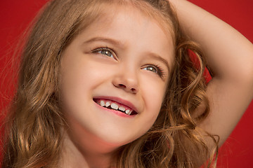 Image showing The happy teen girl standing and smiling against red background.