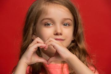 Image showing The happy teen girl standing and smiling against red background.