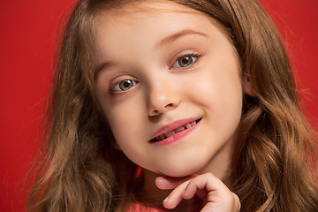 Image showing The happy teen girl standing and smiling against red background.